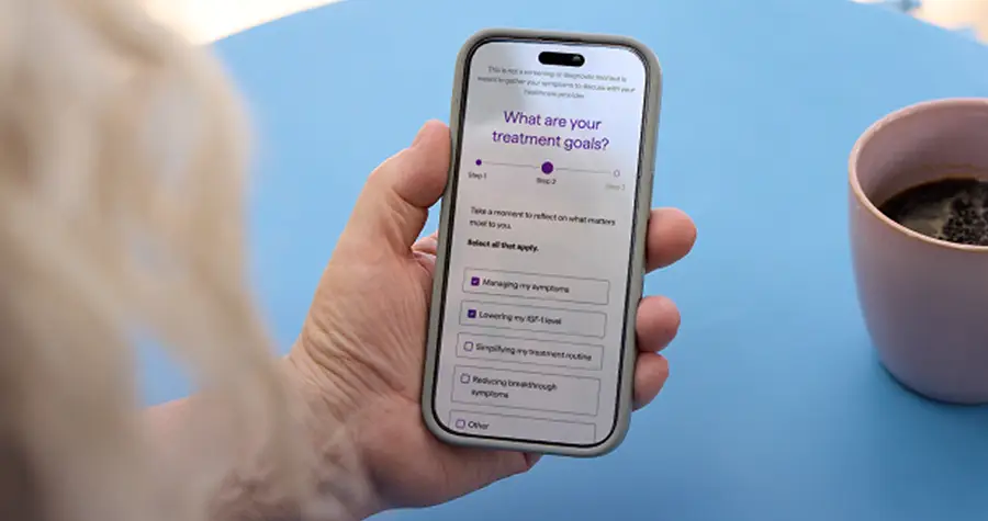 Person holding a smartphone showing the Doctor Discussion Guide intake questionnaire.